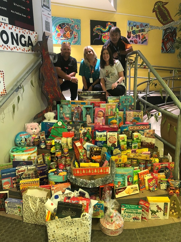 A group stands by a large pile of food and toys.