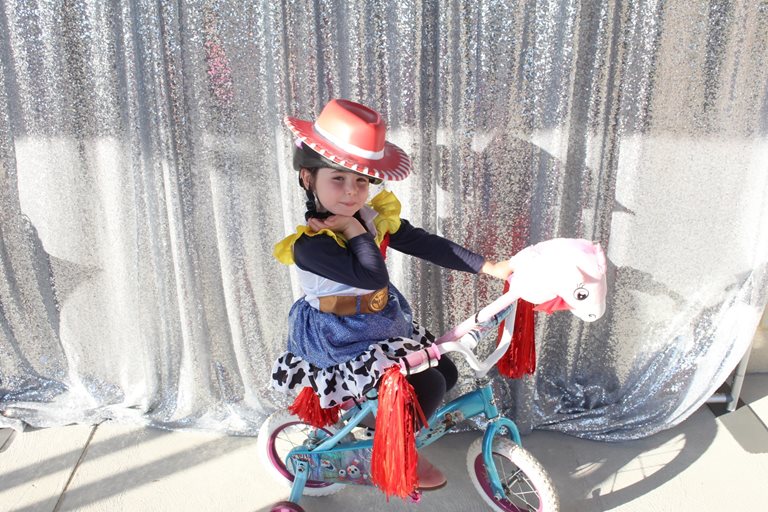 A child in cowgirl costume on a bike