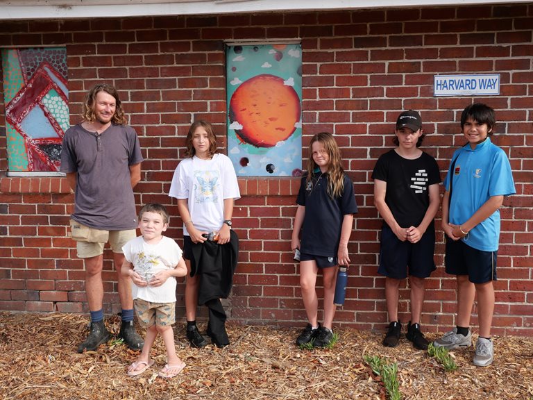 Artist Nathan Hoyle poses outside the Medina Sheds with the youths who helped paint artworks.