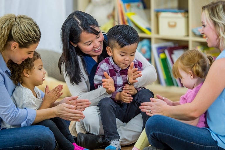 Young Children in a circle clapping hands while sitting on parents lap