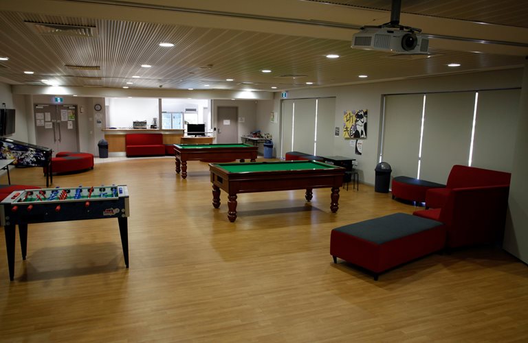 The Zone Youth Space Lounge, set up with several seats, two pool tables, an air hockey table and a pinball machine.