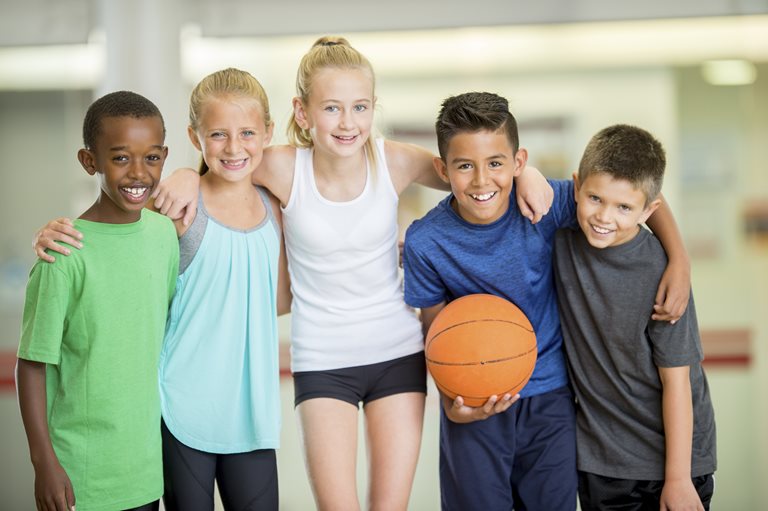 A group of children put their arms around each other and smile.