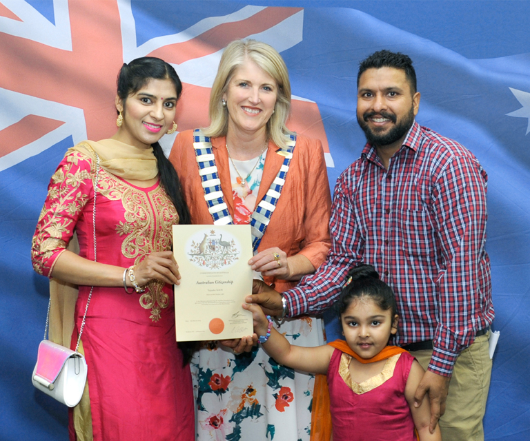 Carol Adams poses with a family of four and their citizenship certificate.