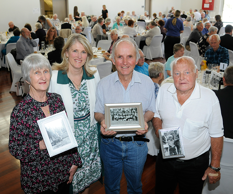 Carol Adams poses with a group of residents holding black and white framed photos.