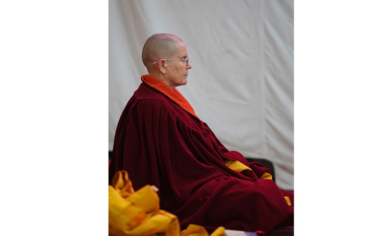 A person in robes sits on the floor meditating.