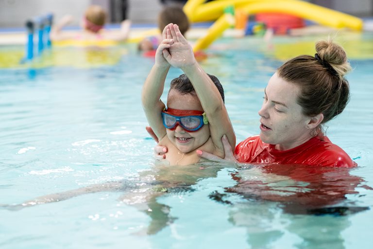 A child being taught to swim by an instructor.