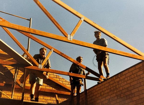Three mean constructing a timber roof frame on a fire station