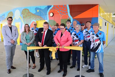 Mayor Peter Feasey and Federal member for Brand Madeleine King cutting a ribbon in front of the mural and sporting club representatives