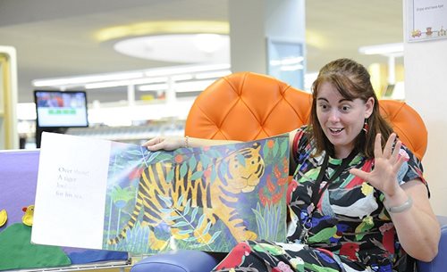 A woman reads a picture book to children.