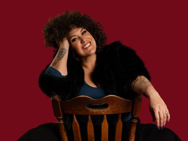 Casey Donovan sitting backwards on a chair smiling