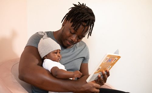 A man reads a book to a baby.