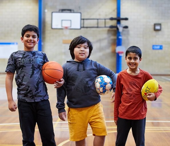 Three young boys holding sports balls