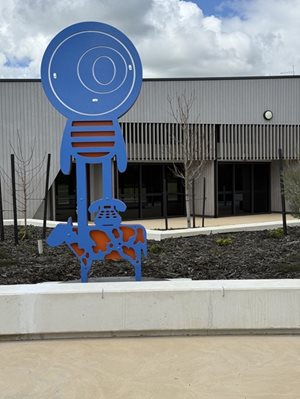 Sculptural artwork of a blue and orange central figure, vintage telephone and cow
